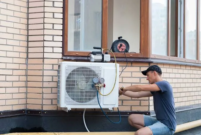 Technician installing an outdoor air conditioner on a brick wall