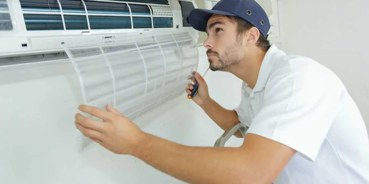 Technician replacing a wall air conditioner filter