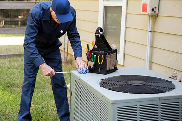 Technician servicing a residential outdoor air conditioner in a yard