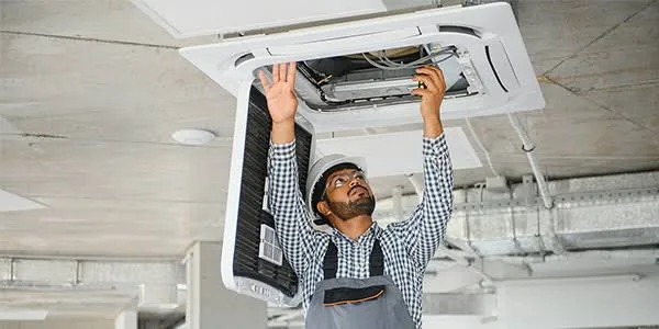 Technician servicing a ceiling air cassette for airflow