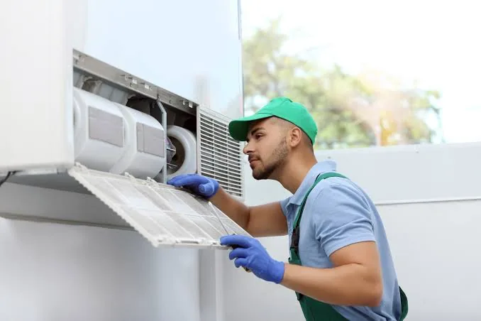 Technician inspecting a dirty indoor air handler filter
