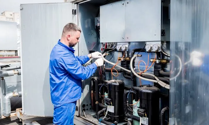 Technician working on rooftop heating and cooling equipment