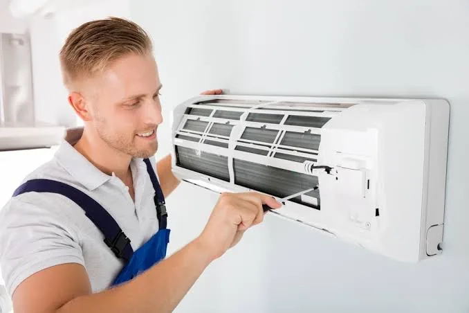 Technician checking filters on a wall-mounted indoor air unit